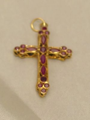 un gros plan d'une croix en or ornée de pierres roses