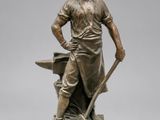 statue en bronze représentant un forgeron avec une enclume, posée sur un socle en marbre