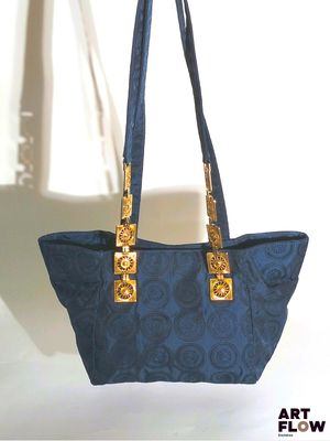 un sac à main bleu et or accroché à un crochet devant un mur blanc