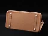 an image of a tan leather purse on a black background