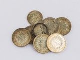 some old coins sitting on top of each other on a white surface