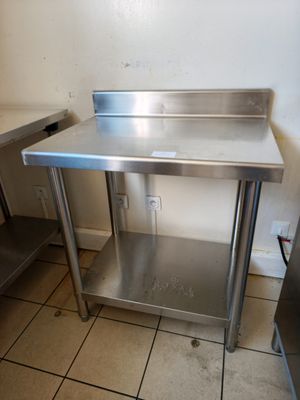 une table de travail en acier inoxydable dans une cuisine équipée d'un évier