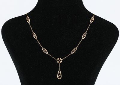 un mannequin noir portant une chaîne en or et un long pendentif