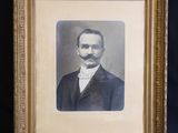 une vieille photo d'un homme moustachu dans un cadre doré