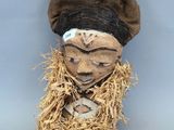 une image représentant un masque en bois surmonté d'un chapeau