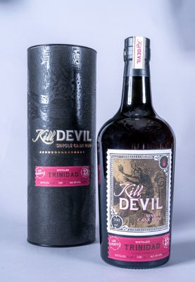 une bouteille de rhum Red Devil posée à côté d'une boîte noire sur une surface blanche