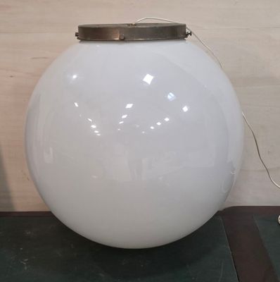 une grande lampe sphérique blanche posée sur une table près d'un mur