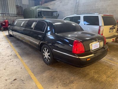 a black limousine parked in a parking lot next to other cars