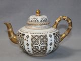 a white tea pot with gold decoration on it
