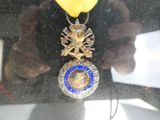 une médaille d'or à laquelle est accroché un ruban bleu et jaune
