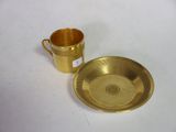 une tasse et une soucoupe dorées posées sur une table blanche