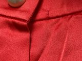 the back of a red dress with a pearl button on it