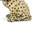 a figurine of a leopard sitting on a white surface