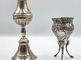 deux vases en argent posés l'un à côté de l'autre sur une surface blanche