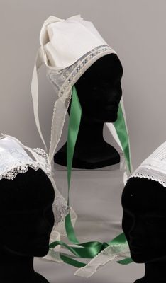 three mannequin heads wearing white bonnets with green ribbons