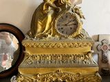 une horloge en or posée sur une table à côté d'un miroir