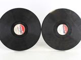 two black vinyl records sitting side by side on a white surface