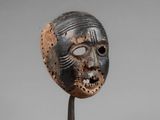 a close up of a wooden mask on a metal stand