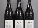 Trois bouteilles de vin rouge sont alignées sur une table en verre
