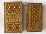 two old books sitting side by side on a white surface