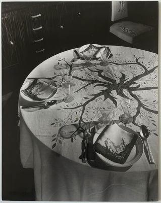 photographie en noir et blanc d'une table sur laquelle sont posés des assiettes et des couverts