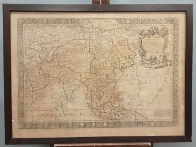 une vieille carte de l'Asie, encadrée dans un cadre en bois, posée sur une table