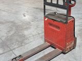 a forklift in a warehouse with pallets in the background