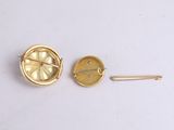 two gold tone buttons and a pin on a white surface