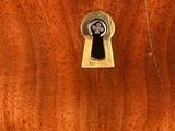 a wooden chest of drawers with a keyhole on the front