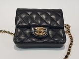 a black purse with a gold chain on a white surface