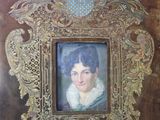 tableau représentant une femme, dans un cadre doré, sur fond marron