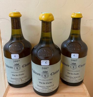 three bottles of wine sitting on a wooden shelf in front of a wall