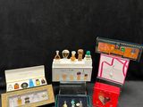 four miniature bottles of perfume and a box of perfume on a black background