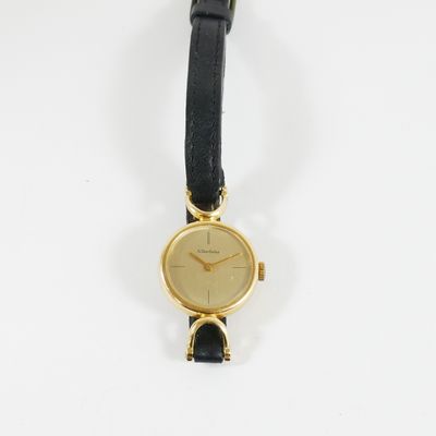 gros plan d'une montre sur une surface blanche avec un bracelet noir