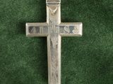 une croix en argent sur un tissu vert, avec un porte-clés au milieu