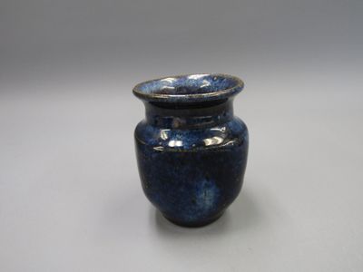 un vase bleu posé sur une table à fond blanc