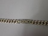 a close up of a silver chain with a name on it