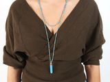 une femme portant un pull marron et un collier bleu orné d'un pendentif en turquoise