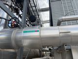 a large metal pipe with a green sign on the side of it