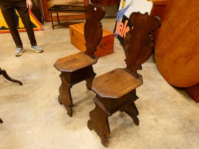 two wooden stools sitting in a room with a painting on the wall