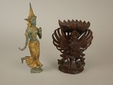 une statue représentant une femme debout à côté d'un vase posé sur une table