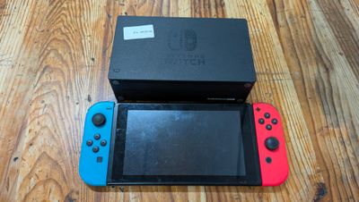 une Nintendo Switch Lite posée par terre à côté d'une boîte