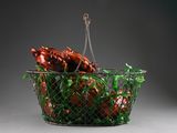 a wire basket filled with meat and vegetables on a gray surface