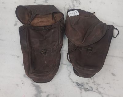une paire de bottes en cuir marron posées sur un sol en marbre, avec une étiquette sur la semelle