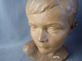 a clay head of a young boy on a blue background