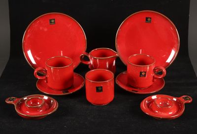 un ensemble d'assiettes et de tasses rouges posées sur une table noire