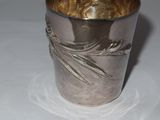 a silver cup with a design on it sitting on a table