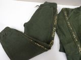 two pairs of green pants with gold writing on them sitting on a white surface
