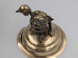 brass figurine of a turtle on a pedestal on a white background