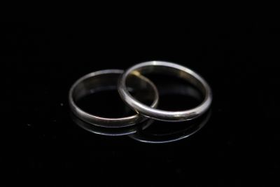 two wedding rings on a black surface with reflection